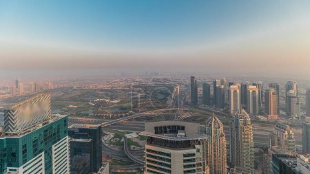 Photo for Panorama of Dubai Marina with JLT skyscrapers and golf course  during sunset, Dubai, United Arab Emirates. Aerial view from above towers. City skyline with rooftops - Royalty Free Image