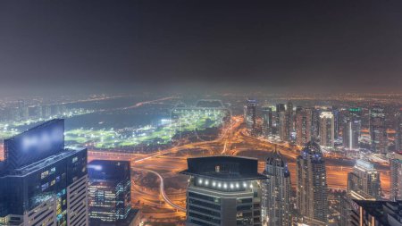 Photo for Panorama of Dubai Marina with JLT skyscrapers and golf course night , Dubai, United Arab Emirates. Aerial view from above towers. City lights illumination - Royalty Free Image