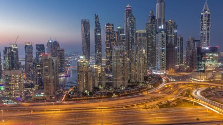 Photo for Skyscrapers of Dubai Marina with illuminated highest residential buildings day to night transition  after sunset with traffic on a highway. Aerial top view from JLT district - Royalty Free Image