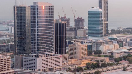 Téléchargez les photos : Immeubles de bureaux à Dubaï Internet City et Media City district transition aérienne de nuit au jour. Trafic sur jonction et gratte-ciel avec lever et soleil réfléchis par le verre - en image libre de droit