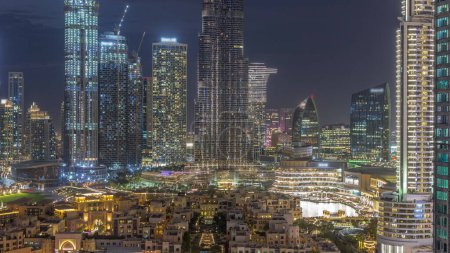 Téléchargez les photos : Dubaï Transition du jour au soir du centre-ville avec le plus haut gratte-ciel et d'autres tours autour de la vieille ville et de la fontaine après le coucher du soleil à Dubaï, Émirats arabes unis. Lumières allumées. - en image libre de droit