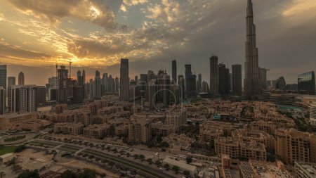 Téléchargez les photos : Sunset over Dubai Downtown  with tallest skyscraper and other towers view from the top in Dubai, United Arab Emirates. Rays of light and cloudy orange sky - en image libre de droit