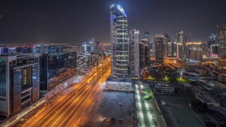 Photo for Dubai's business bay and downtown towers aerial night panoramic . Rooftop view of some office skyscrapers and new towers under construction - Royalty Free Image