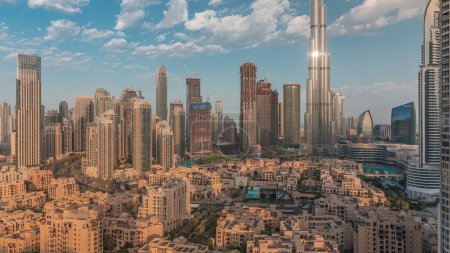 Foto de Dubai Mañana en el centro con sol reflejado desde el rascacielos más alto y otras torres vista desde la cima durante el amanecer, Emiratos Árabes Unidos. Casas tradicionales del casco antiguo y nubes rosadas - Imagen libre de derechos
