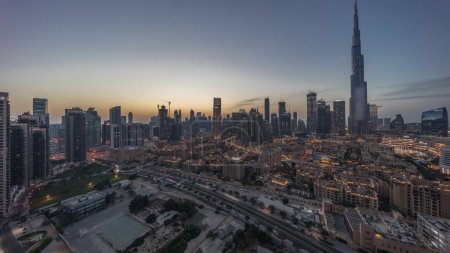 Téléchargez les photos : Dubai Downtown day to night transition  with tallest skyscraper and other towers panoramic view from the top during sunset in Dubai, United Arab Emirates. Lights turning on. - en image libre de droit