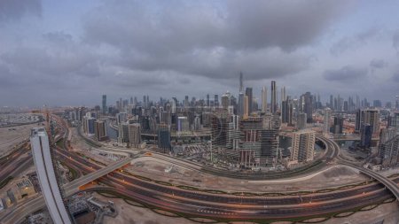 Foto de Skyline panorámico de Dubai con la bahía de negocios y la noche del centro de distrito. Vista aérea de gran angular de muchos rascacielos modernos durante el amanecer con reflejos de vidrio. Emiratos Árabes Unidos. - Imagen libre de derechos