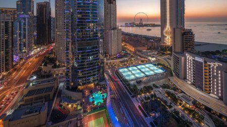 Téléchargez les photos : Vue panoramique sur la marina de Dubaï et la région de JBR et la célèbre transition de jour à nuit de la grande roue. Plages de sable doré dans le golfe Persique avec coucher de soleil - en image libre de droit