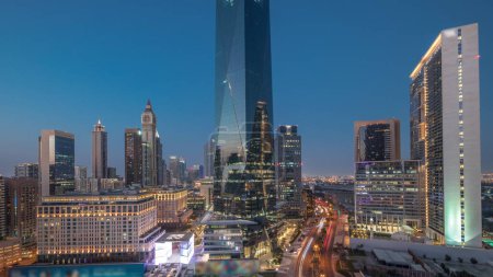 Téléchargez les photos : Dubai International Quartier financier transition jour-nuit. Vue aérienne panoramique des tours de bureaux d'affaires après le coucher du soleil. gratte-ciel avec hôtels et centres commerciaux près du centre-ville - en image libre de droit