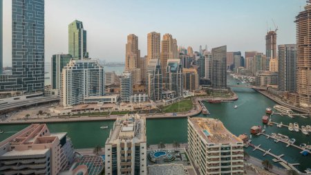 Téléchargez les photos : Panorama showing Dubai Marina with several boat and yachts parked in harbor and skyscrapers around canal aerial . Towers of JBR district on a background - en image libre de droit