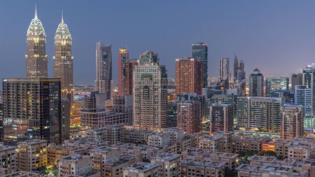 Photo for Skyscrapers in Barsha Heights district and low rise buildings in Greens district aerial day to night transition . Dubai skyline with internet city towers - Royalty Free Image