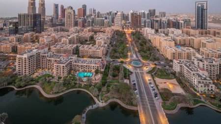 Téléchargez les photos : Des gratte-ciel dans le quartier de Barsha Heights et des immeubles de faible hauteur dans le quartier des Verts transition aérienne du jour à la nuit panoramique. Dubai skyline avec des palmiers et des arbres le long de la route - en image libre de droit