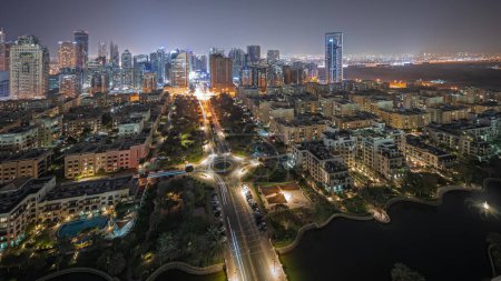 Téléchargez les photos : Panorama showing skyscrapers in Barsha Heights district and low rise buildings in Greens district aerial night . Dubai skyline with palms and trees - en image libre de droit