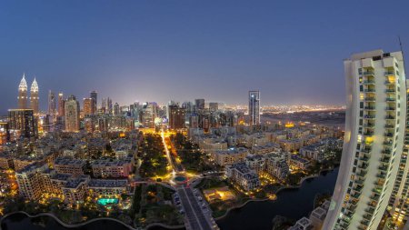 Téléchargez les photos : Panorama avec gratte-ciel dans le quartier de Barsha Heights et bâtiments de faible hauteur dans le quartier des Verts transition aérienne du jour à la nuit. Skyline de Dubaï avec trafic de rue - en image libre de droit