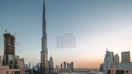 Photo for Dubai Downtown panoramic cityscape with tallest skyscrapers around aerial night to day transition . Construction site of new towers and busy roads with traffic from above - Royalty Free Image