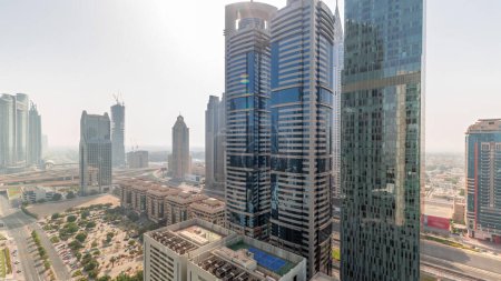 Photo for Aerial panorama of Dubai International Financial District with many skyscrapers  during all day with shadows moving fast. Traffic on a road near parking lot with rooftop tennis court. Dubai, UAE. - Royalty Free Image
