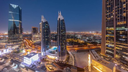 Photo for Aerial view of Dubai International Financial District with many skyscrapers day to night transition panoramic after sunset. Traffic on roads near shopping avenue with rooftop walking area. Dubai, UAE. - Royalty Free Image