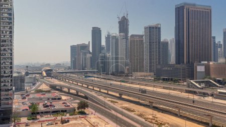 Foto de Dubai Marina rascacielos y Sheikh Zayed carretera con metro aéreo durante todo el día con sombras moviéndose rápido. Tráfico en una autopista cerca de torres modernas, Emiratos Árabes Unidos - Imagen libre de derechos