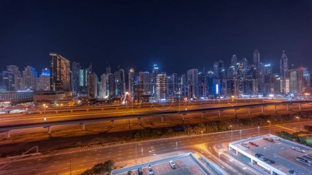 Foto de Panorama de Dubai marina bloque más alto de rascacielos durante toda la noche con las luces apagadas. Vista aérea desde el distrito JLT a edificios de apartamentos, hoteles y torres de oficinas cerca de la autopista. - Imagen libre de derechos