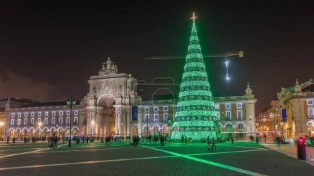Téléchargez les photos : Commerce square illuminated and decorated at Christmas time in Lisbon night timelapse hyperlapse. Commercio square with christmas tree and people tourists crowd around, city of europe - en image libre de droit