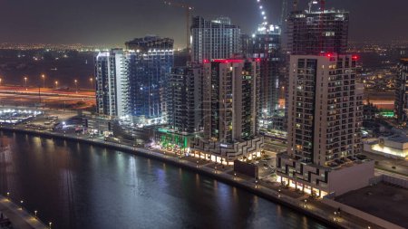 Téléchargez les photos : Tours à Business Bay passage aérien de jour à nuit timelapse à Dubaï, Émirats arabes unis. Vue du site de construction d'en haut avec canal - en image libre de droit