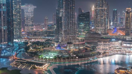 Foto de Vista aérea de Dubai ciudad día a noche timelapse transición en el centro de la ciudad. skyline futurista de la ciudad con rascacielos iluminados y fuente desde arriba. - Imagen libre de derechos