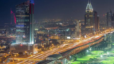 Téléchargez les photos : Vue aérienne de Sheikh Zayed Road dans la zone de Dubai Internet City, de jour comme de nuit. gratte-ciel et circulation sur une autoroute avec station de métro après le coucher du soleil - en image libre de droit