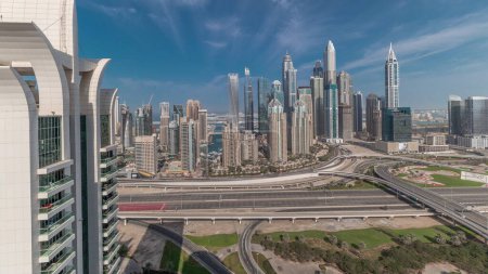 Téléchargez les photos : Panorama montrant Dubai Marina et la ville des médias avec parcours de golf carrefour autoroute spaghetti jonction timelapse. Les plus hauts gratte-ciel et la circulation. Vue aérienne du quartier JLT - en image libre de droit