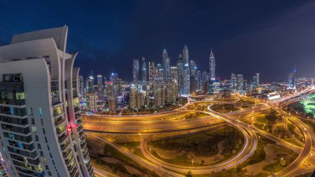 Photo for Panorama of Dubai Marina after sunset highway intersection spaghetti junction day to night transition timelapse. Illuminated tallest skyscrapers on a background. Aerial top view from JLT district. - Royalty Free Image