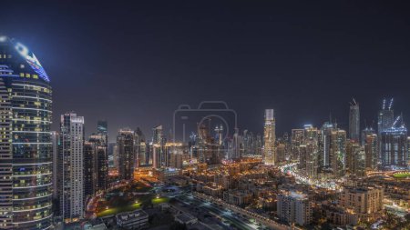 Photo for Panorama showing Dubai's business bay and downtown towers with old town aerial night timelapse. Rooftop view of some skyscrapers and new towers under construction - Royalty Free Image
