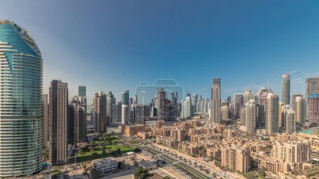 Photo for Panorama showing Dubai's business bay and downtown towers aerial morning timelapse. Rooftop view of some skyscrapers and new buildings under construction with thaditional houses of old town district - Royalty Free Image