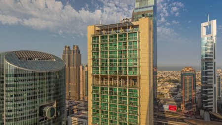 Téléchargez les photos : Dubai centre financier international gratte-ciel avec de longues ombres matin aérien timelapse pendant le lever du soleil. Lumière chaude orange sur les tours - en image libre de droit