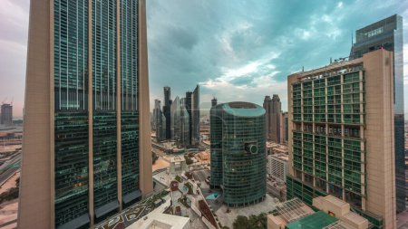 Photo for Dubai international financial center skyscrapers panorama aerial night to day transition timelapse. Illuminated towers view from above before sunrise with cloudy colorful sky - Royalty Free Image
