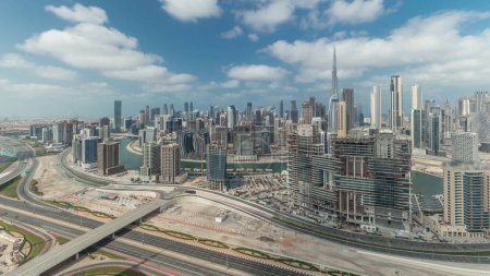 Foto de Panorama que muestra el horizonte de Dubai con la bahía de negocios y el timelapse del centro de distrito. Vista aérea de muchos rascacielos modernos con cielo azul nublado. Emiratos Árabes Unidos. - Imagen libre de derechos