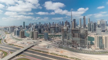 Foto de Panorama que muestra el horizonte del distrito del centro de Dubái con timelapse de la bahía de negocios. Vista aérea de muchos rascacielos modernos con cielo azul nublado. Emiratos Árabes Unidos. - Imagen libre de derechos
