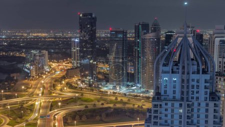 Photo for Huge highway crossroad junction between JLT district and Dubai Marina intersected by Sheikh Zayed Road aerial during night. Golf course near illuminated towers and skyscrapers with busy traffic - Royalty Free Image