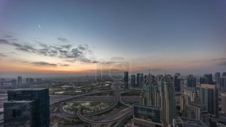 Téléchargez les photos : Énorme carrefour routier entre le quartier JLT et Dubai Marina recoupé par Sheikh Zayed Road matin aérien timelapse panoramique. Terrain de golf près des tours et gratte-ciel éclairés - en image libre de droit