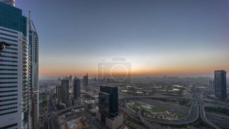 Foto de Vista panorámica aérea de la ciudad de los medios de comunicación y el distrito de alturas al barsha con campo de golf mañana timelapse desde Dubai marina. Torres y rascacielos con tráfico en una intersección de carreteras desde arriba - Imagen libre de derechos