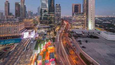 Foto de Dubai International Distrito financiero noche timelapse con el tráfico en una calle. Vista aérea panorámica de las torres de oficinas de negocios después del atardecer. Rascacielos con hoteles y centros comerciales cerca del centro - Imagen libre de derechos
