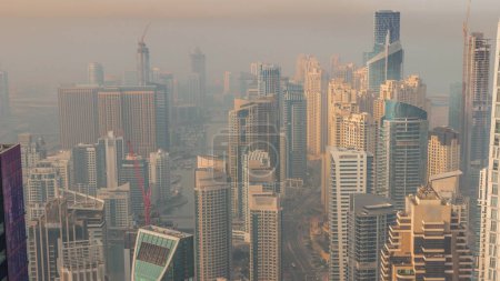Foto de Vista panorámica del horizonte de Dubai Marina mañana borrosa que muestra un canal artificial rodeado de rascacielos a lo largo del timelapse aéreo de la costa. Yates flotantes y barcos antes del amanecer. DUBAI, Emiratos Árabes Unidos - Imagen libre de derechos