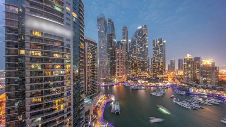 Téléchargez les photos : Dubai marina gratte-ciel les plus hauts avec des fenêtres éclatantes et des yachts dans la nuit aérienne du port après le coucher du soleil. Vue sur les immeubles d'appartements, les hôtels et les immeubles de bureaux, développement résidentiel moderne des EAU - en image libre de droit