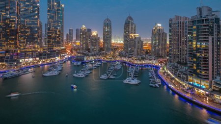 Foto de Bahía de yates de lujo en la ciudad día aéreo a la noche timelapse transición en Dubai marina. Rascacielos modernos a lo largo del paseo marítimo y barcos flotando en el puerto - Imagen libre de derechos