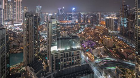 Téléchargez les photos : Panorama montrant la vue aérienne d'une grande ville futuriste timelapse nocturne. Baie d'affaires et quartier du centre-ville avec de nombreux gratte-ciel et maisons traditionnelles, Dubaï, Émirats arabes unis skyline. - en image libre de droit