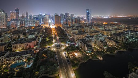 Foto de Panorama mostrando rascacielos en el distrito de Barsha Heights y edificios de poca altura en el timelapse aéreo nocturno del distrito de Greens. Dubai skyline con palmeras y árboles - Imagen libre de derechos