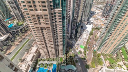 Téléchargez les photos : Timelapse du paysage urbain aérien avec l'architecture moderne du centre-ville de Dubaï. Regardez vers le bas pour de grands gratte-ciel et des tours avec des ombres se déplaçant rapidement. Nouveau chantier de construction. - en image libre de droit