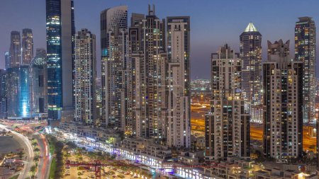 Téléchargez les photos : Bay Avenue avec des tours modernes développement résidentiel dans Business Bay aérien de jour à la nuit timelapse de transition, Dubaï, EAU. Gratte-ciel après le coucher du soleil - en image libre de droit