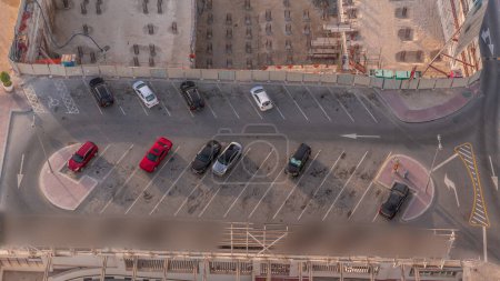 Téléchargez les photos : Vue de dessus du parking avec de nombreuses voitures se déplaçant dans et hors du temps. Vue aérienne d'en haut avec quelques chantiers à proximité - en image libre de droit