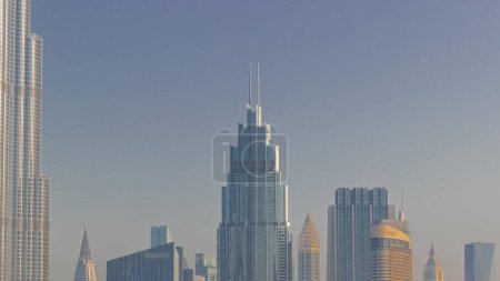 Foto de Edificios altos en el centro de Dubái, Emiratos Árabes Unidos. Reflejos de la superficie de cristal de los rascacielos durante la salida del sol con rayos de luz solar - Imagen libre de derechos