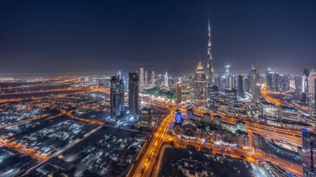 Foto de Vista aérea de las torres más altas del centro de Dubái skyline y zona de arroyo día a noche timelapse transición. Distrito financiero y área de negocios en la ciudad urbana inteligente. Rascacielos y edificios de gran altura - Imagen libre de derechos