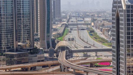 Téléchargez les photos : Occupé Sheikh Zayed Road aérienne pendant toute la journée, métro ferroviaire et gratte-ciel modernes autour dans la ville de Dubaï de luxe avec des ombres se déplaçant rapidement. Trafic lourd sur une autoroute avec de nombreuses voitures. Émirats arabes unis - en image libre de droit
