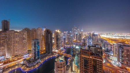 Foto de Panorama de varios rascacielos en el bloque recidencial más alto de Dubai Marina día aéreo a noche timelapse transición con canal artificial. Muchas torres en el distrito JBR y yates después del atardecer - Imagen libre de derechos